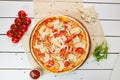 Freshly baked pizza with smoked chicken fillet and gorgonzola cheese served on wooden background with tomatoes, sauce and herbs. Royalty Free Stock Photo