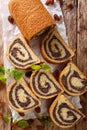 Freshly baked poppy roll with raisins, decorated with mint close-up on a table. Vertical top view Royalty Free Stock Photo