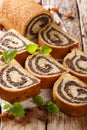 Freshly baked poppy roll with raisins, decorated with mint close-up on a table. vertical