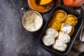 Freshly baked pumpkin cinnamon rolls or cinnabon with cream cheese on a dark stone background. Homemade seasonal autumn homemade