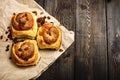 Freshly baked rolls with cinnamon with spices and raisins on parchment paper. View from above. Sweet homemade pastries. Close-up. Royalty Free Stock Photo