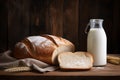 freshly baked rustic bread on a napkin and a bottle of milk on wooden background