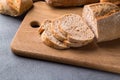 Freshly baked sliced bread on wooden cutting board on the grey stone table, close up Royalty Free Stock Photo