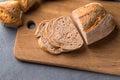 Freshly baked sliced bread on wooden cutting board on the grey stone table, close up Royalty Free Stock Photo