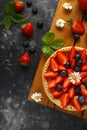 Freshly baked Strawberry custard tarts on wooden tray with camomiles, summer theme