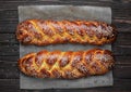 Freshly baked sweet braided bread loaf challah bread on a baking paper, dark wooden background, top view