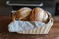 Freshly baked tasty rhye flour round loafs of rhye breads in wicker basket with grey linen kitchen towel at wooden table in bakery Royalty Free Stock Photo