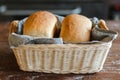 Freshly baked tasty white flour rectangular breads in wicker basket with grey linen kitchen towel at wooden table in bakery Royalty Free Stock Photo