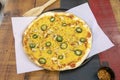 A freshly baked thin crust pizza with chicken, yellow cheese, sliced jalapenos on a parchment paper lined baking sheet Royalty Free Stock Photo