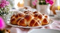 Freshly baked traditional cross buns for Happy Easter. Festive sweet pastries on rustic tray next to bright flowers Royalty Free Stock Photo