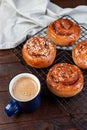 Freshly baked traditional Swedish cinnamon buns Kanelbulle with cup of coffee or cappuccino, on wooden background, vertical