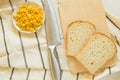 Freshly baked traditional wheat bread, corn grains and knife on linen kitchen towel, flat lay Royalty Free Stock Photo