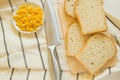 Freshly baked traditional wheat bread, corn grains and knife on linen kitchen towel, flat lay Royalty Free Stock Photo