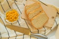 Freshly baked traditional wheat bread, corn grains and knife on linen kitchen towel, flat lay Royalty Free Stock Photo