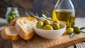 Freshly baked white bread, with olive oil and green olives, on a wooden board. Mediterranean food.