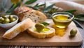 Freshly baked white bread, with olive oil and green olives, on a wooden board. Mediterranean food.