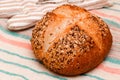 Freshly baked whole grain loaf of bread sprinkled with seeds of flax, sesame, sunflower seeds on linen towel. Close-up Royalty Free Stock Photo