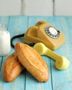 Freshly bakery food and old telephone in retro style. White bread loafs and glass of milk. Light rustic breakfast on