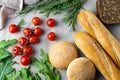 Freshly bakes bread, herbs, tomatoes and greens on a table, overhead flat lay Royalty Free Stock Photo