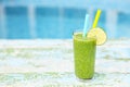 Freshly blended green fruit smoothie in glass with straw