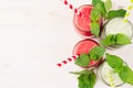 Freshly blended green and red fruit smoothie close up in glass jars with straw, mint leafs, top view. White wooden board backgroun Royalty Free Stock Photo