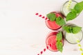 Freshly blended green and red fruit smoothie close up in glass jars with straw, mint leafs, top view. White wooden board backgroun Royalty Free Stock Photo