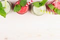 Freshly blended green and red fruit smoothie of strawberry and apple in glass jars with straw, mint leafs, top view. White wooden Royalty Free Stock Photo