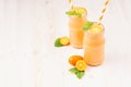 Freshly blended orange citrus kumquat fruit smoothie in glass jars with straw, mint leaf, cute ripe berry, copy space.
