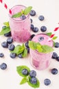 Freshly blended violet blueberry fruit smoothie in glass jars with straw, mint leaves, berries. White wooden board background. Royalty Free Stock Photo