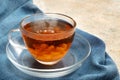 freshly brewed black tea with a cream cloud in a glass cup, steaming hot drink on a blue napkin, copy space