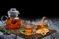 Freshly brewed black tea with mint and cookies, honey and glass teapot on a wooden table