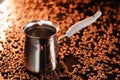 Freshly brewed coffee in cezve on a dark golden background next to scattered roasted coffee beans Royalty Free Stock Photo