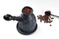 Freshly brewed coffee with foam in a pot of black clay and a steel measuring spoon with fried coffee beans. Royalty Free Stock Photo