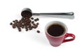 Freshly brewed coffee with foam  in a red cup and a steel measuring spoon with roasted coffee beans Royalty Free Stock Photo