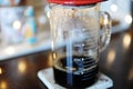 Freshly brewed coffee in a graduated glass measuring container. Close up. Lights in the background