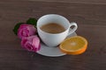 Freshly brewed coffee served with beautiful rose flowers and slice of orange. Royalty Free Stock Photo