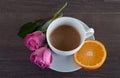 Freshly brewed coffee served with beautiful rose flowers and slice of orange. Royalty Free Stock Photo