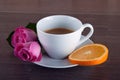 Freshly brewed coffee served with beautiful rose flowers and slice of orange. Royalty Free Stock Photo