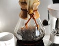 Freshly brewed drip coffee close up in sun rays. Manual coffee grinder. Home brewing