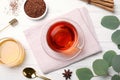 Freshly brewed rooibos tea, dry leaves, honey and spices on white wooden table, flat lay