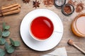 Freshly brewed rooibos tea, scattered dry leaves, honey and spices on wooden table, flat lay