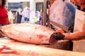 Freshly caught tuna being cut by unrecognizable fisherman at the store in the market