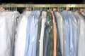 Freshly cleaned men`s shirts and ladies blouses in a dry cleaning, hung on hangers and protected by plastic film. Royalty Free Stock Photo