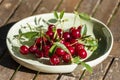 Freshly collected red cherries in the ceramic bowl.