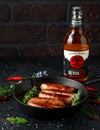 Freshly cooked butchers sausages in skins in cast iron frying pan with Sanford orchards apple cider, Devon, United