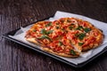Freshly cooked hot pizza and slice with cheese ham meat tomato onion parsley homemade on parchment paper in baking sheet tray Royalty Free Stock Photo