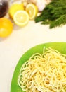 Freshly Italian spaghetti on a green plate are on the kitchen table against a background of vegetables and herbs Royalty Free Stock Photo