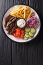 Freshly cooked shawarma plate with beef, french fries, vegetables and sauce close-up. Vertical top view Royalty Free Stock Photo