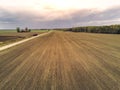 Freshly cultivated farmland with animal trails and small country road, Forest in the background, Cloudy blue sky, Concept Royalty Free Stock Photo