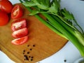 Freshly cut celery, tomatoes, green onion on wooden cutting board next to spiced black pepper Royalty Free Stock Photo